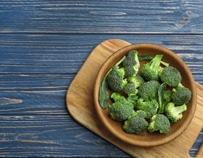 Bowl of fresh broccoli on blue wooden table
